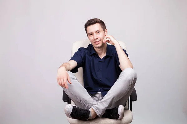 Joven sonriente sentado con los pies en una silla de oficina —  Fotos de Stock