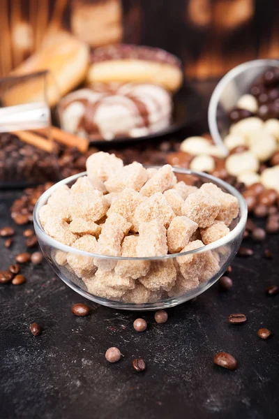 Zucchero di canna in una ciotola di vetro accanto a caramelle e dolci — Foto Stock