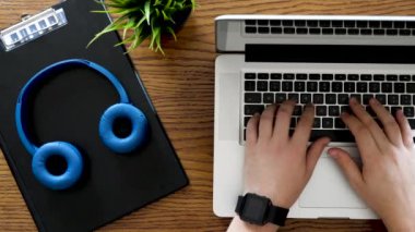 İş raporları ve diyagramları yanında bir masa üzerinde bir dizüstü bilgisayarda yazarak eller