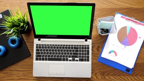 Таблиця вигляду зверху з ноутбуком з зеленим екраном хрому на ньому поруч з кишенями — стокове відео
