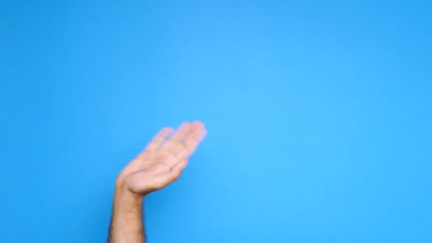 Detailní záběr mužské ruky stoupá na modrém pozadí a začne upuštění od — Stock video