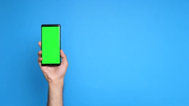 Hand met een telefoon met een groen scherm op het — Stockvideo