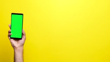 Yeşil bir ekran ile bir telefon üzerinde tutan adam el