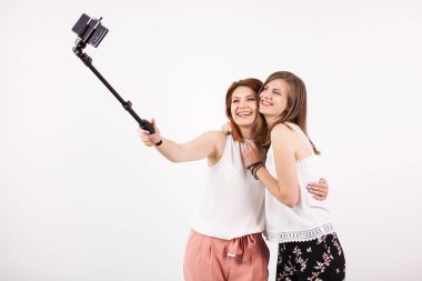 İki güzel genç kadın bir selfie bir selfie sopa ile alarak