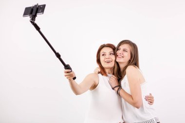İki güzel genç kadın bir selfie bir selfie sopa ile alarak