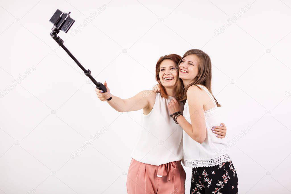 Two beautiful young woman taking a selfie with a selfie stick