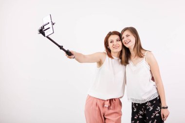 İki güzel genç kadın bir selfie bir selfie sopa ile alarak