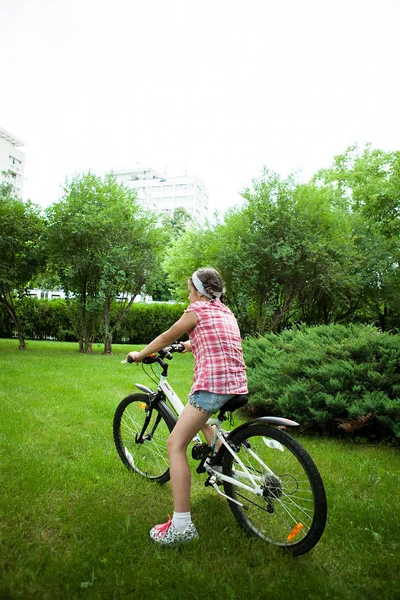 Chica montando su bicicleta en el parque — Foto de Stock