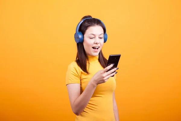 Mulher bonito mensagens de texto em seu telefone enquanto ouve música — Fotografia de Stock