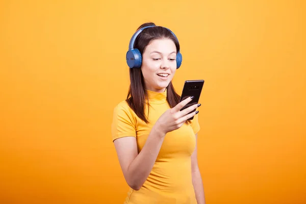Мила Молода Жінка Смс Телефоні Слухаючи Музику Студії Жовтому Фоні — стокове фото