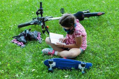 İyi bir kitap üzerinde çim andreading oturan genç kız