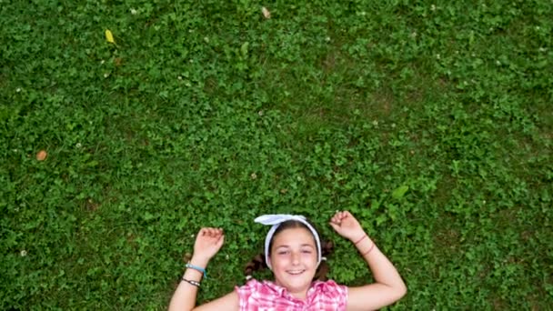 Кавказская молодая девушка лежит на траве в парке — стоковое видео
