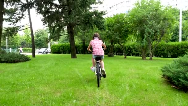 Rückansicht eines hübschen Teenagermädchens auf einem Fahrrad im Park — Stockvideo
