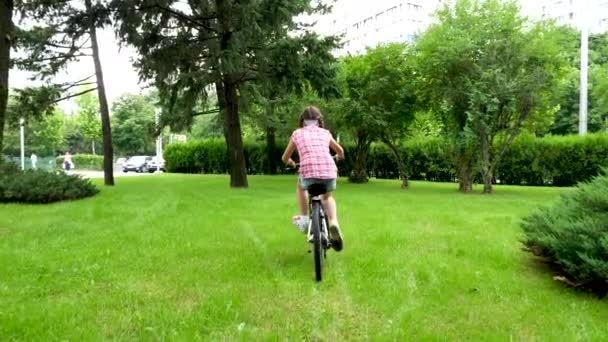 Baksidan på ganska tonårig flicka på cykel i parken — Stockvideo