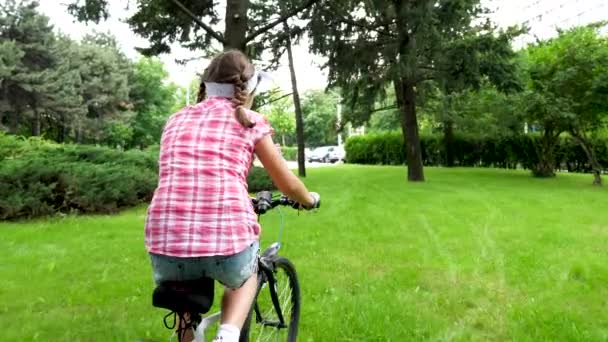 Menina adolescente feliz monta uma bicicleta no parque — Vídeo de Stock