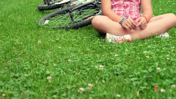 Przesunąć w górę dziewczyna siedzi na trawie w parku — Wideo stockowe