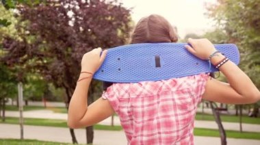 Omzuna bir kaykay ile genç kız kameraya benziyor