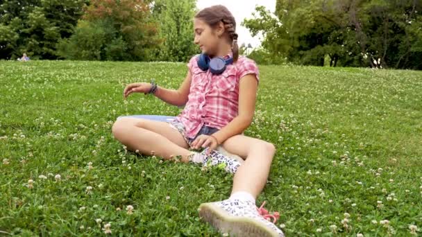 Милая молодая девушка сидит в траве — стоковое видео