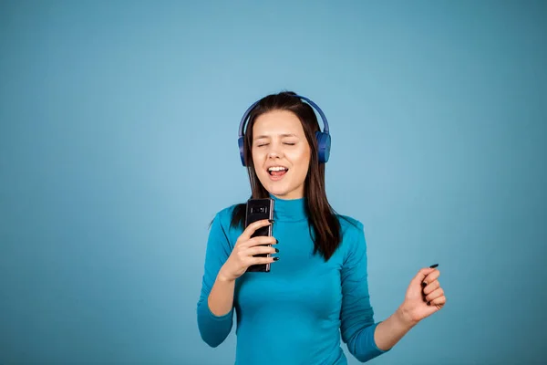 Bonito jovem mulher cantando em seu telefone enquanto dança — Fotografia de Stock