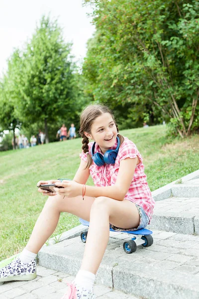 Tjej att ha kul med hennes telefon i parken — Stockfoto
