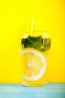 Sarı arka plan üzerinde organik ve taze limonata ile cam