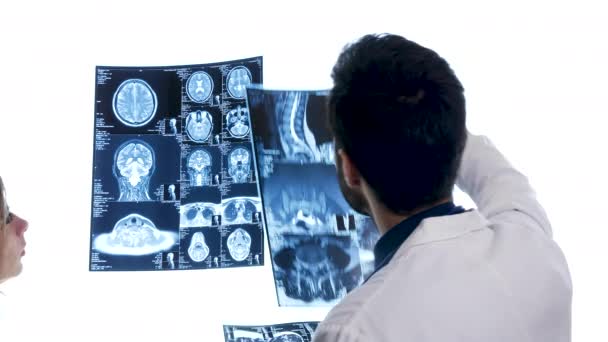Doctor placing three MRI scans on big white screen — Stock Video