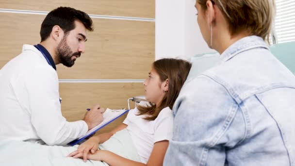 Médico fazendo pergunta diferente para uma menina adolescente deitada na cama do hospital — Vídeo de Stock