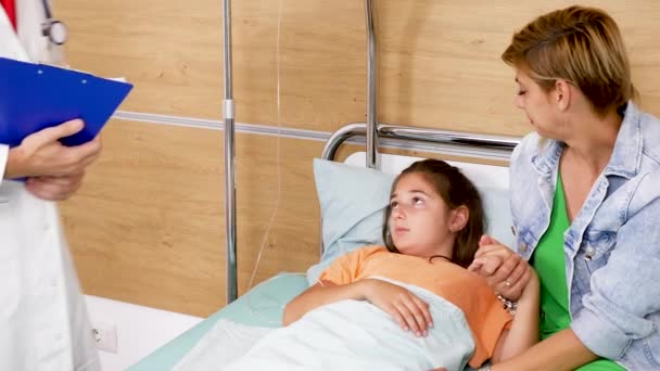 Doktor přijde v nemocničním pokoji a kontroluje dospívající dívka srdce — Stock video