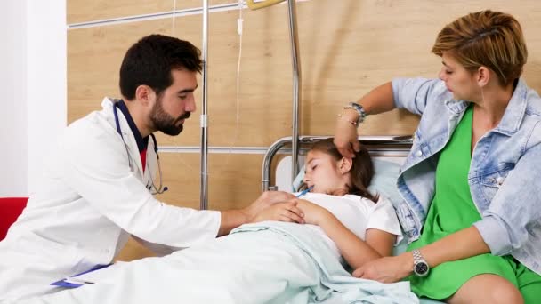Больная девочка лежит на больничной койке и доктор проверяет ее температуру — стоковое видео