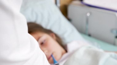 Doktor bir dijital termometre sırayla sonra küçük bir kız sıcaklığı denetler