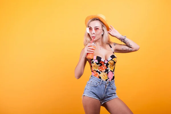 Jovem com cabelo loiro bebendo suco de laranja com óculos de sol — Fotografia de Stock