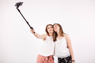 İki güzel genç kadın bir selfie bir selfie sopa ile alarak