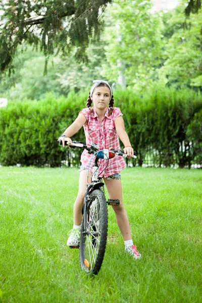 Chica montando su bicicleta en el parque — Foto de Stock