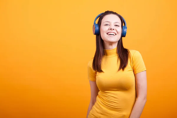 Carino giovane donna sorridente mentre ascolta musica in studio — Foto Stock