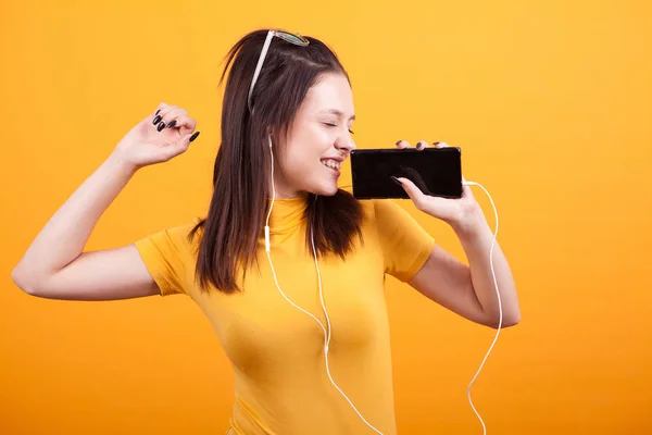 Мила молода жінка співає під час прослуховування музики на своєму телефоні — стокове фото