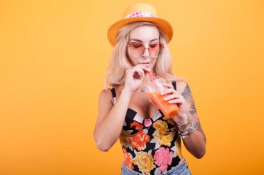 Mutlu kadın Studio sarı arka plan üzerinde portakal suyu içme