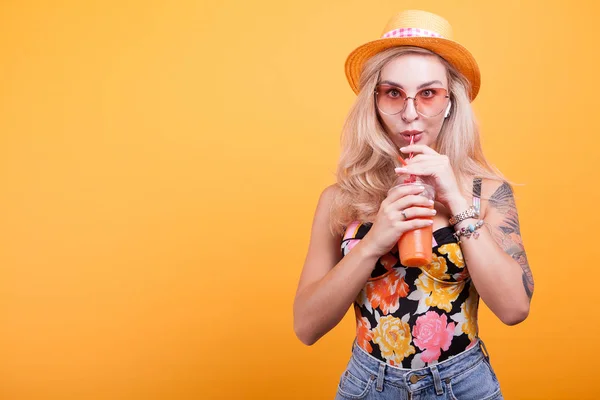 Jeune femme aux cheveux blonds buvant du jus d'orange avec des lunettes de soleil — Photo