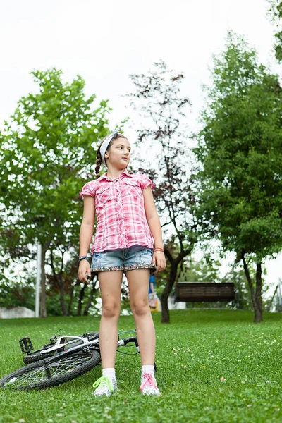 Chica en el parque al lado de su bicicleta — Foto de Stock