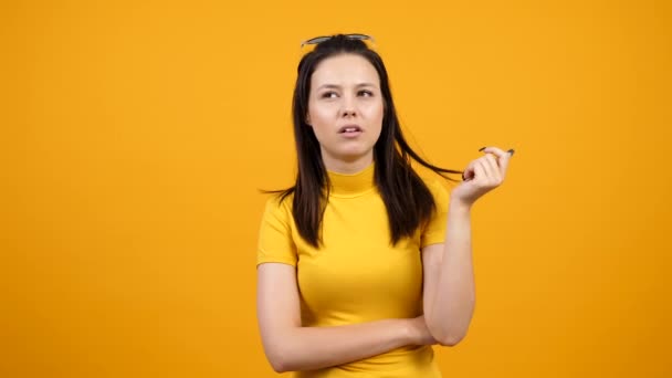 Chica aburrida masticando goma de mascar sobre fondo naranja vivo en el estudio — Vídeos de Stock