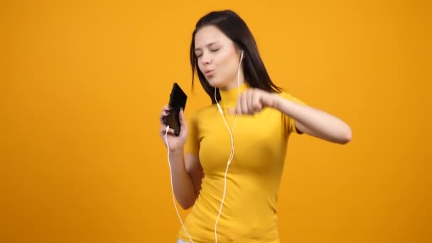 Счастливая женщина танцует и поет, слушая музыку на своем смартфоне — стоковое видео
