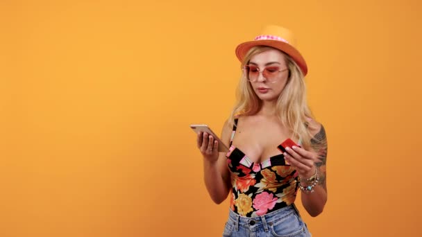 Verward sexy vrouw kijkt naar de credit card en haar smartphone — Stockvideo