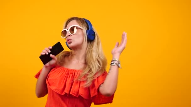 Gelukkig mooie vrouw danst en zingt in haar smartphone — Stockvideo