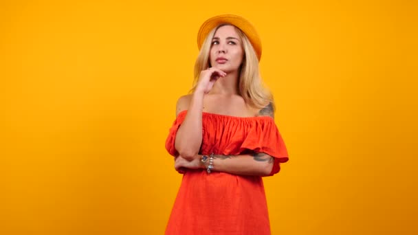 Mujer confundida desconcertada en vestido de verano sobre fondo amarillo naranja — Vídeos de Stock
