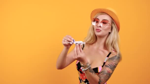 Schöne Blondine mit Hut und Sonnenbrille spielt mit einem Spielzeugflugzeug — Stockvideo