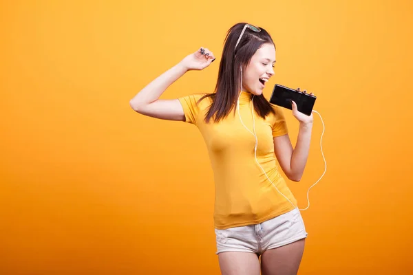 Carina giovane donna che canta sul suo telefono mentre balla — Foto Stock