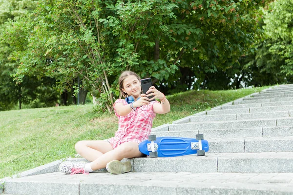 女孩玩她的手机在公园的乐趣 — 图库照片