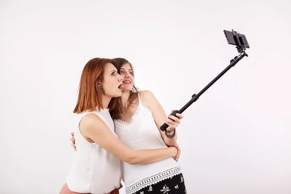 Portrait de deux belles jeunes femmes prenant un selfie avec un bâton de selfie — Photo