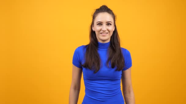 Mujer alegre positiva y alegre mostrando los pulgares hacia arriba sobre fondo de color naranja amarillento — Vídeos de Stock