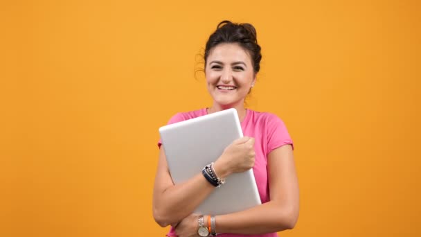 Молодая студентка держит в руках ноутбук и смеется — стоковое видео