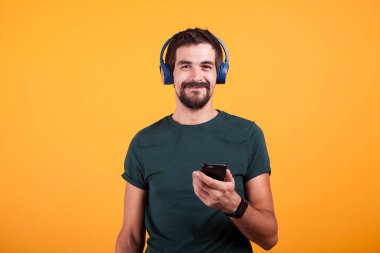Mavi kulaklık ve smartphone onun elinde olan çekici adam sakin ol